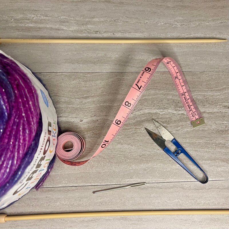 yarn, knitting needles, measuring tape, scissors and tapestry needle